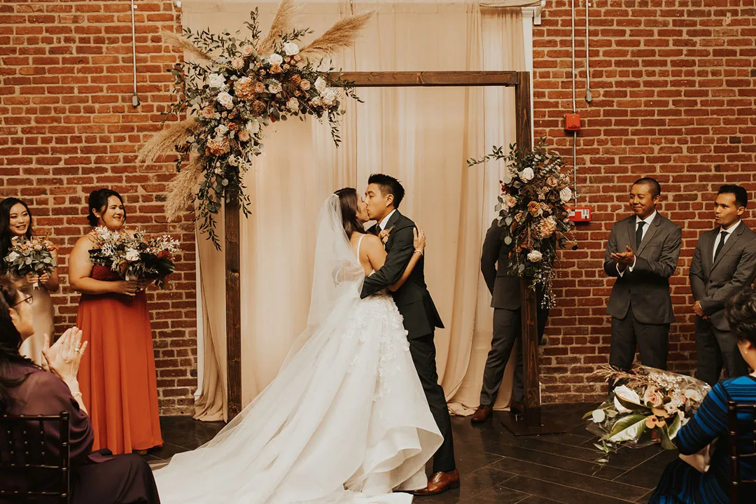 Newlyweds kissing at their ceremony backdrop