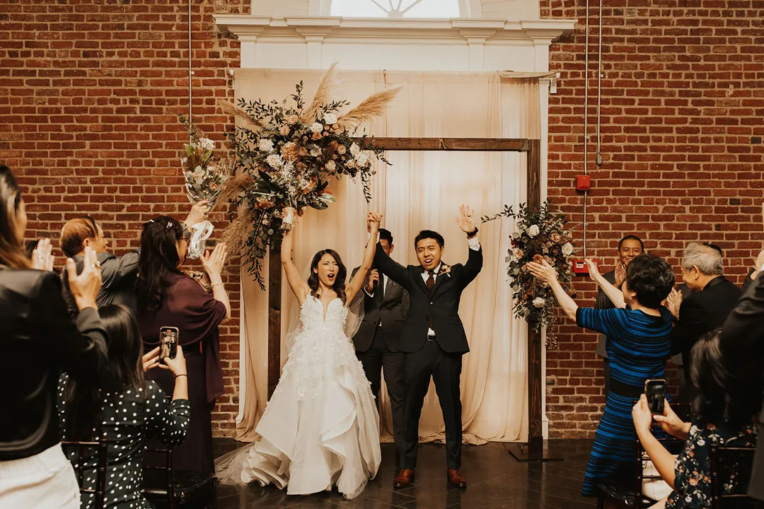 Couple celebrating as their guests raise their arms