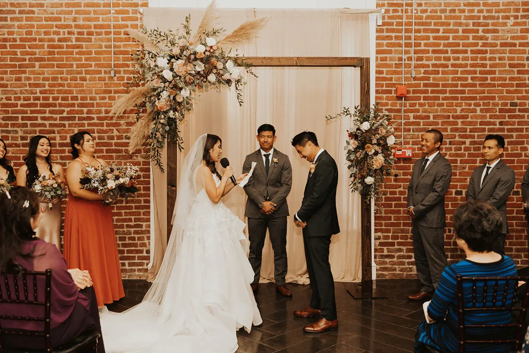Couple exchanging vows under a floral arch