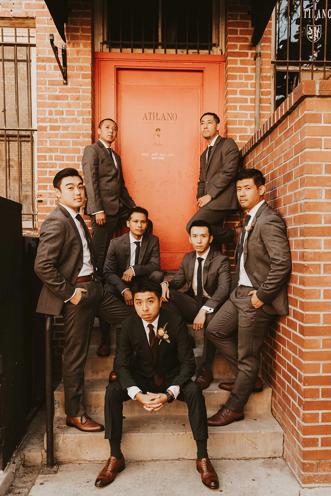Groom and groomsmen posing beside brick steps