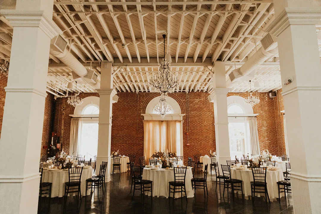Round reception tables beneath ballroom chandeliers