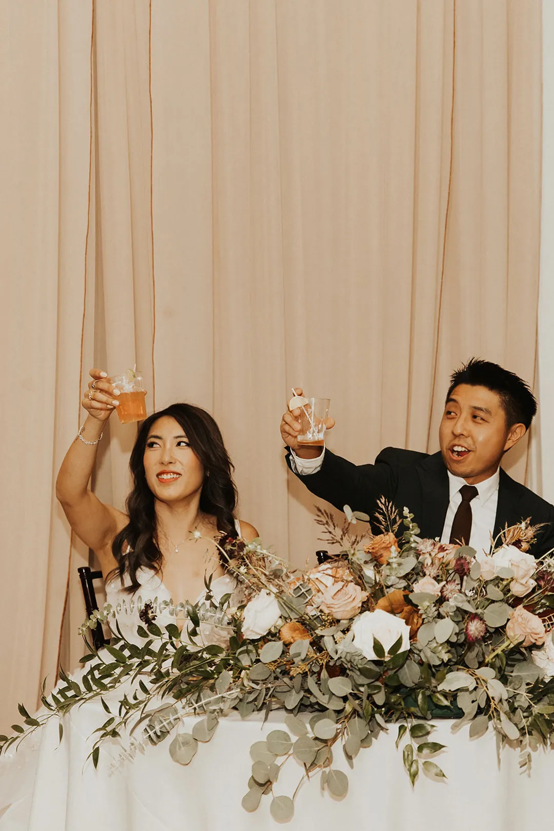 Newlyweds raising drinks at their sweetheart table