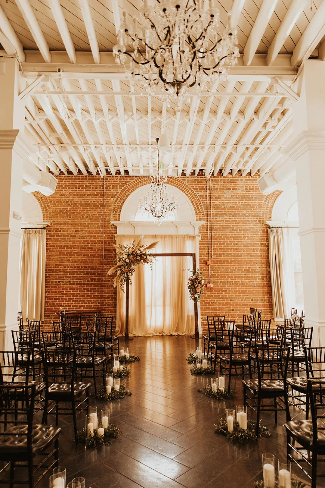 Ceremony chairs beneath white beams and chandeliers
