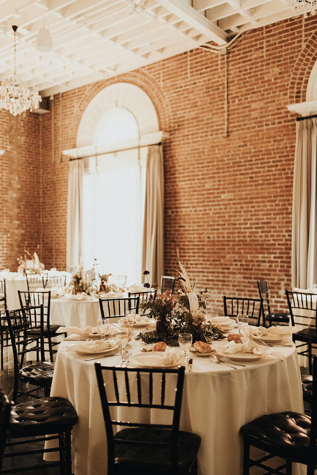 Reception tables beside the ballroom's tall windows