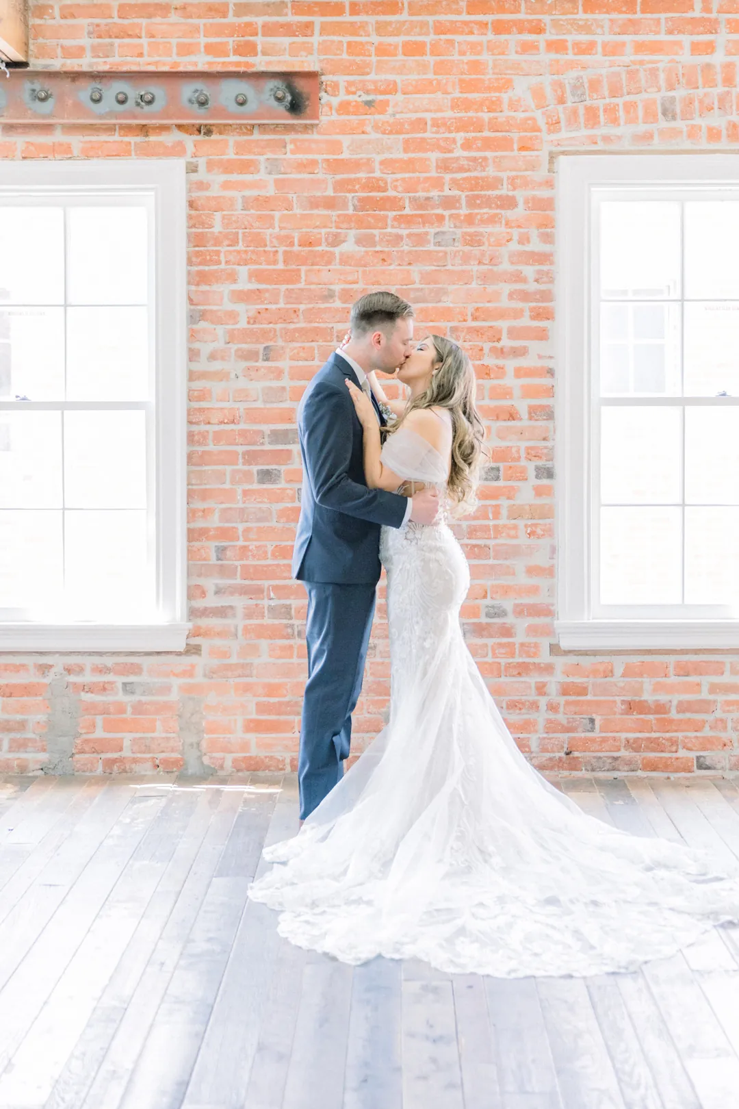 Newlyweds embracing beside tall windows