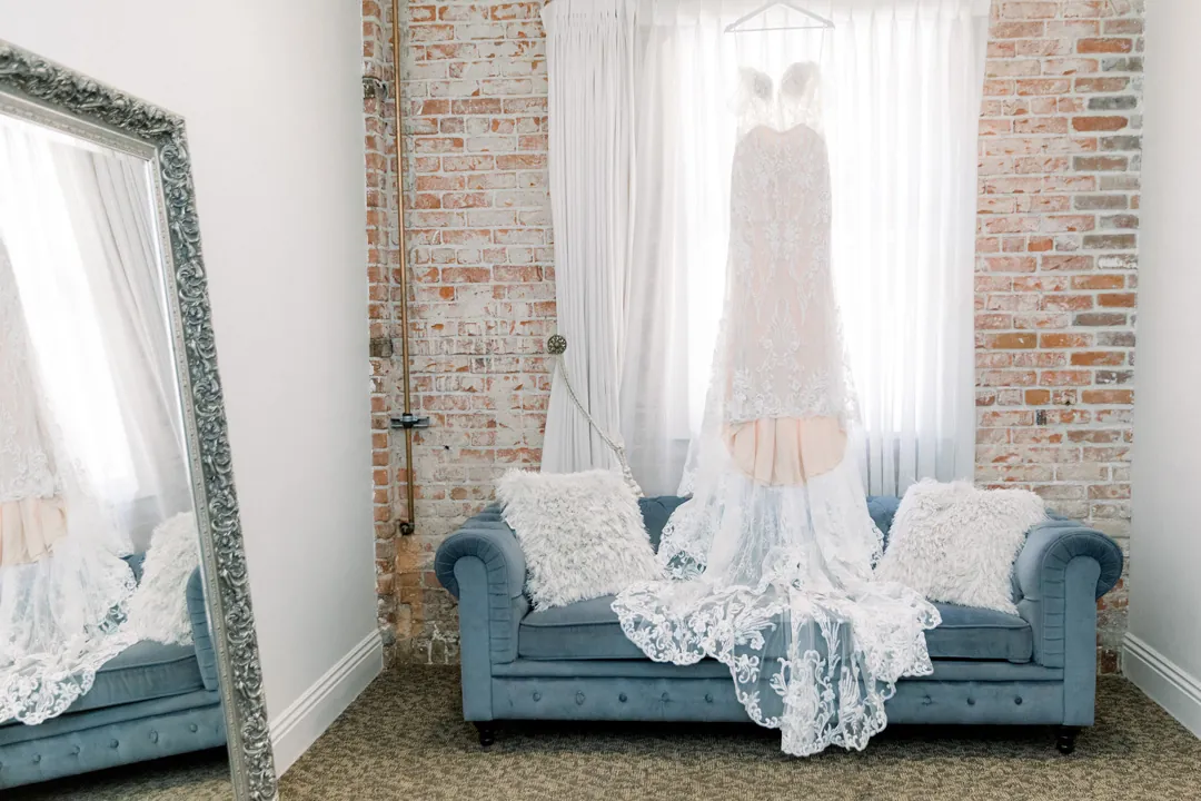 Wedding dress hanging above a gray sofa