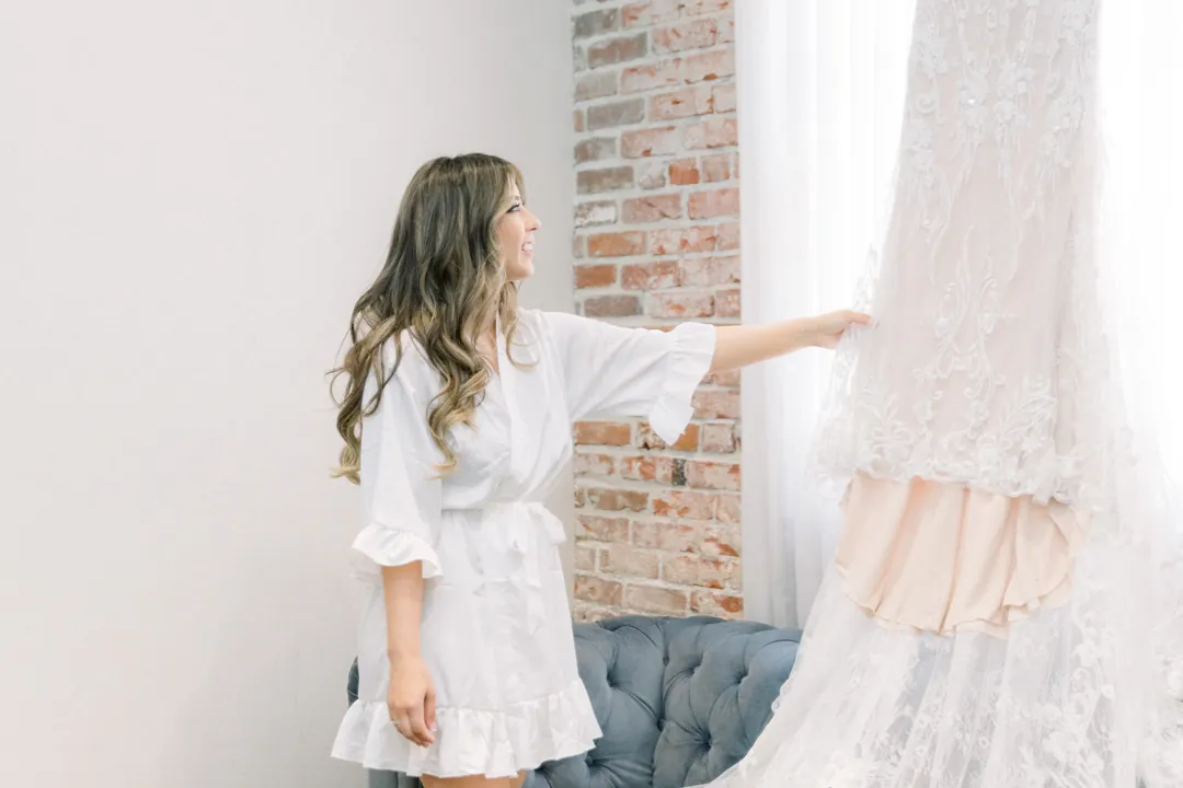 Bride touching her hanging wedding gown