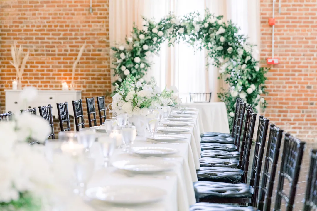 Reception table facing a circular greenery arch