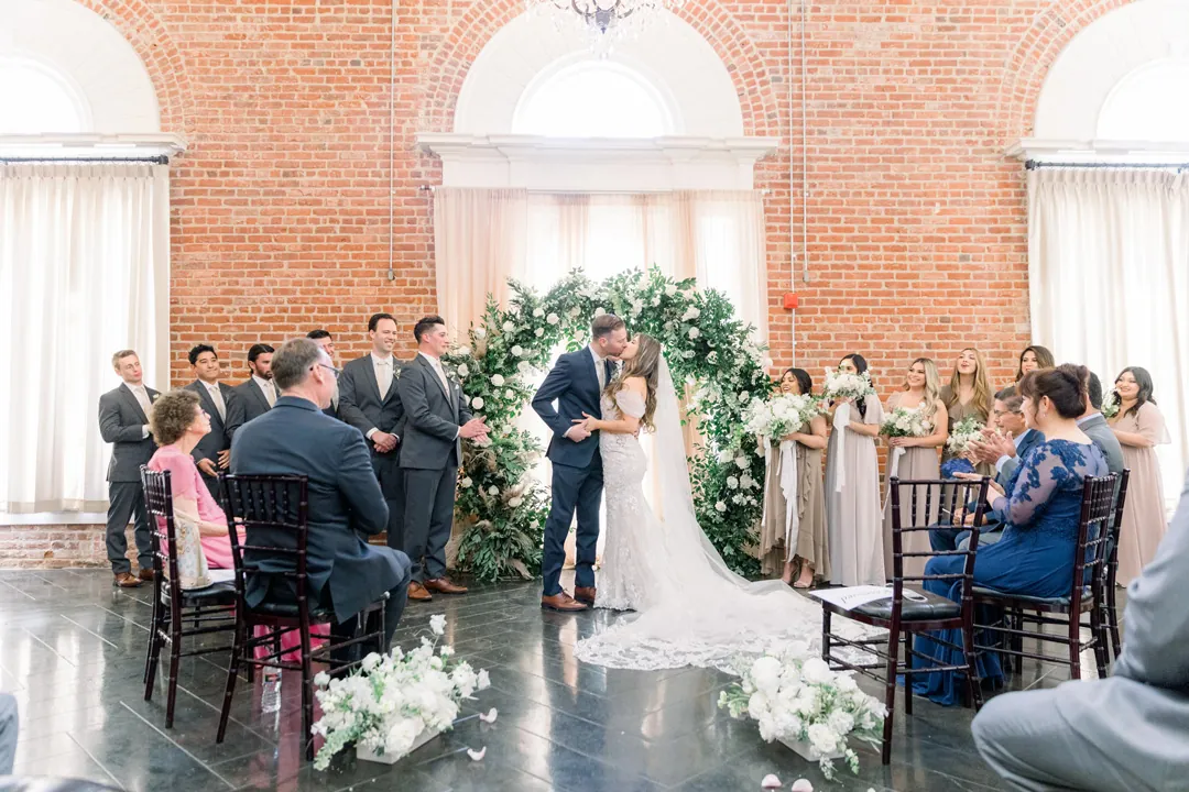 Wedding guests seated along a flower-lined aisle