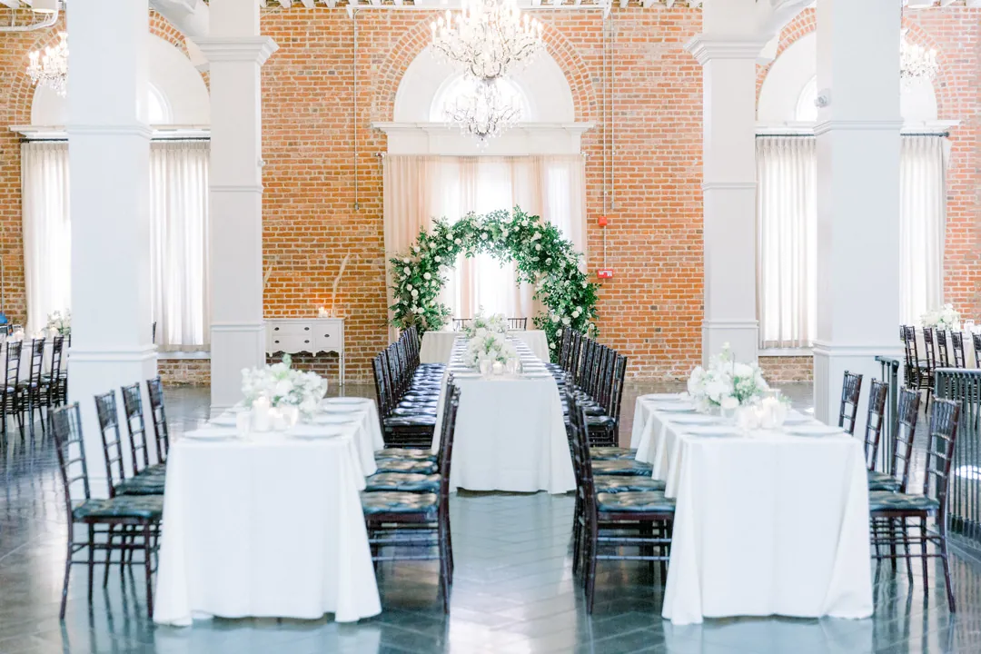 Long reception tables beneath ballroom chandeliers