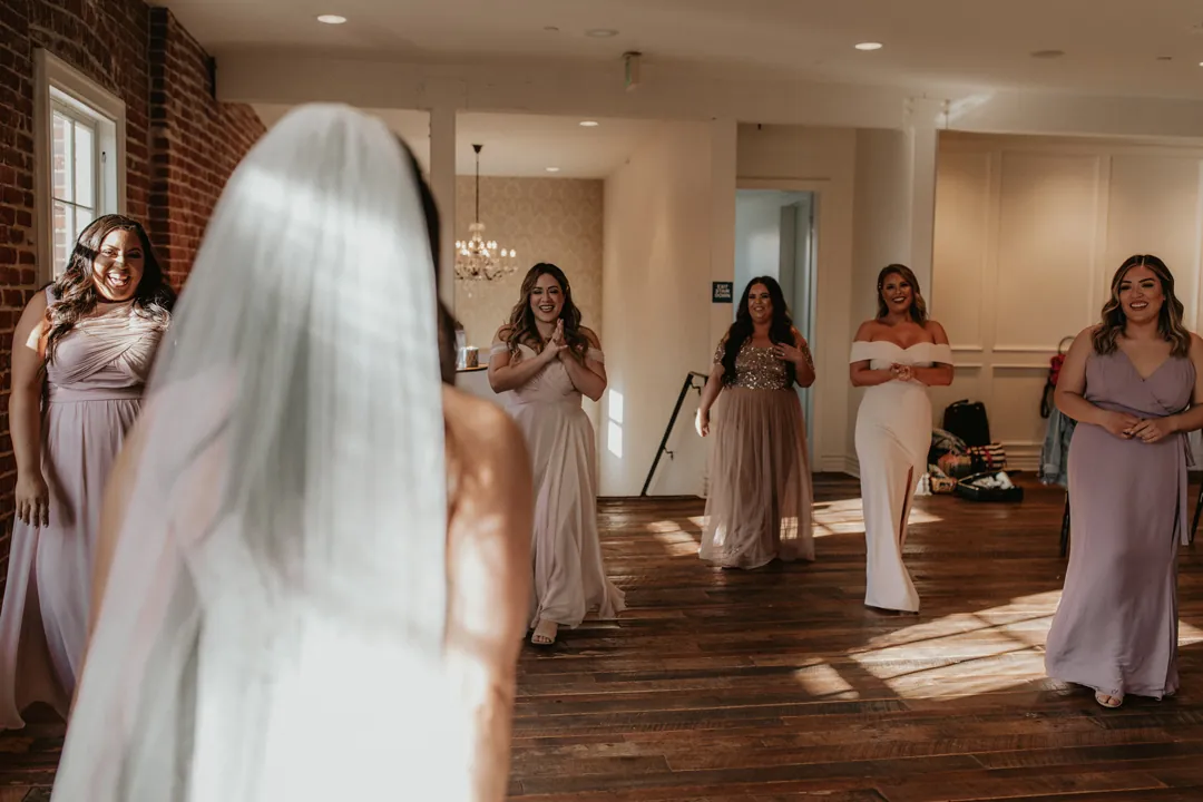 Bride approaching bridesmaids in a sunlit room