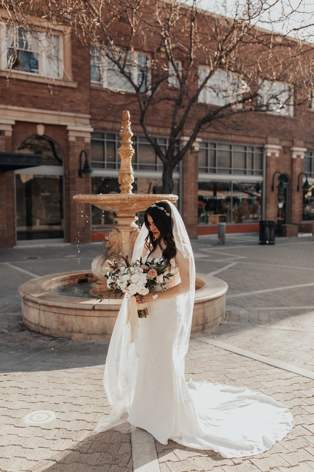 Bride posing beside an outdoor fountain