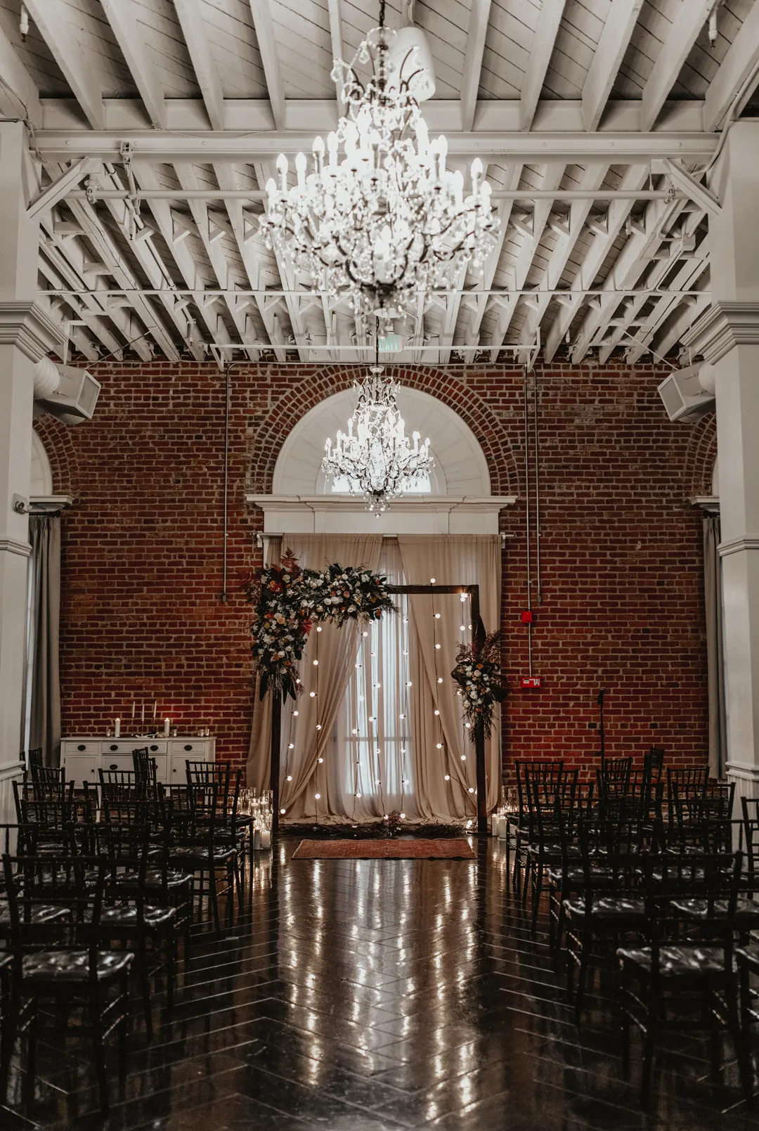 Ceremony chairs beneath chandeliers and white beams