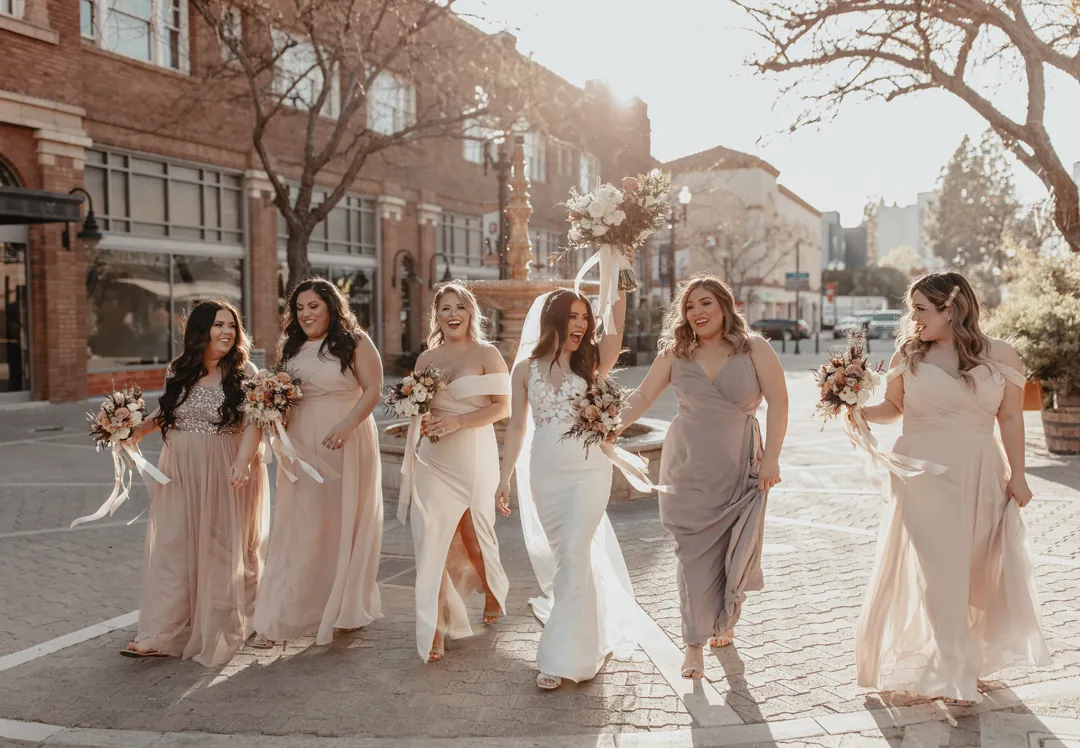 Bride and bridesmaids walking down a city sidewalk
