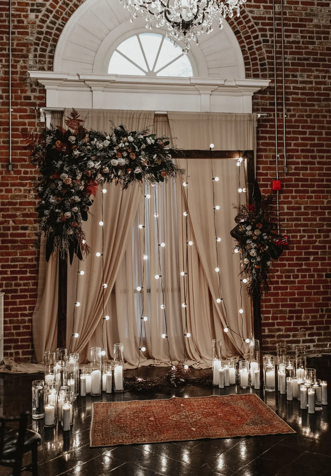 Flower-covered ceremony backdrop with candles