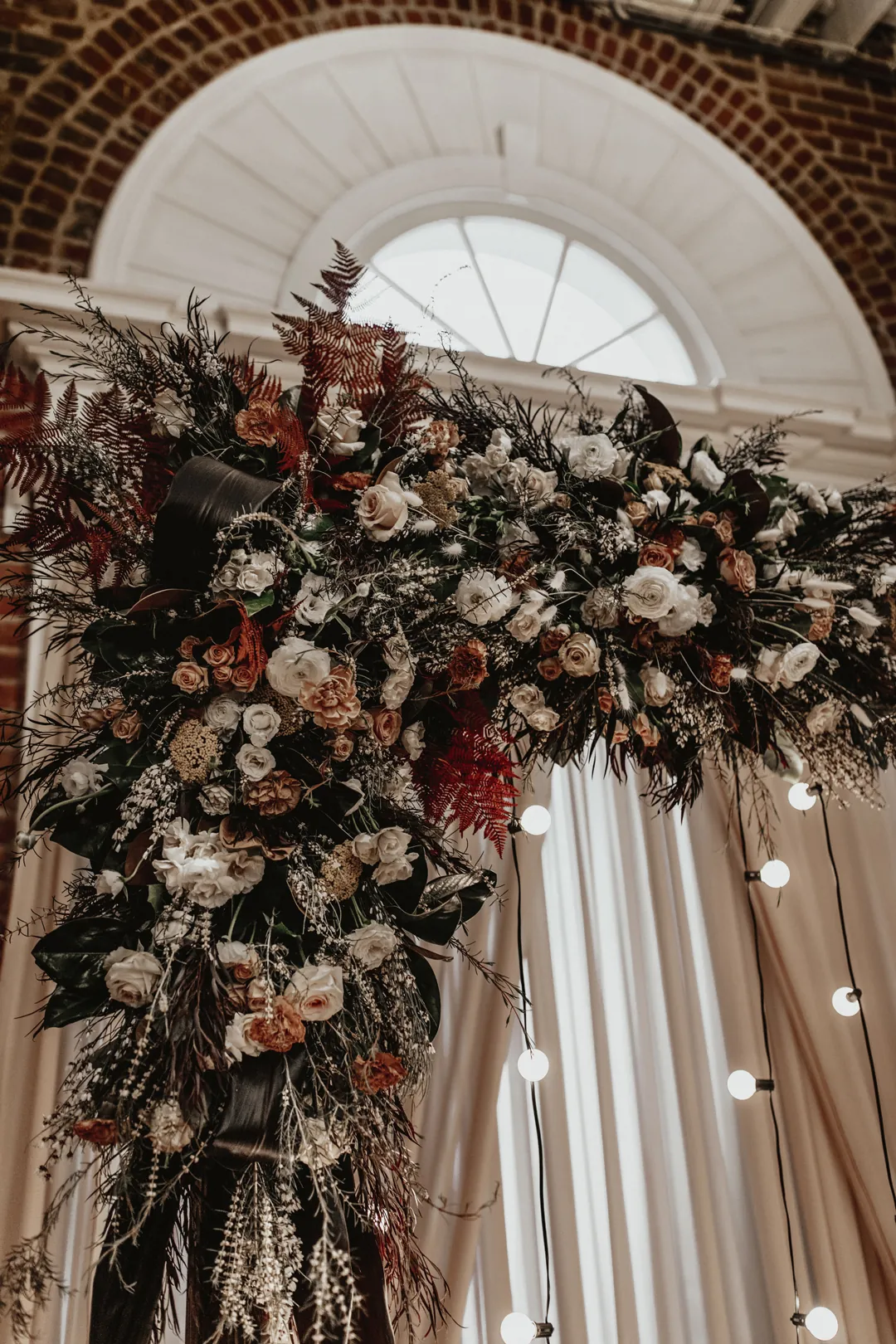 Floral arch and string lights beneath an arched window