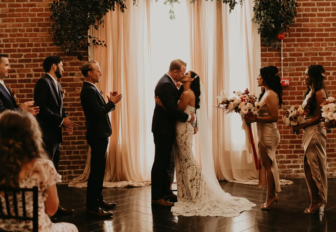 Bride and groom kissing before their ceremony guests