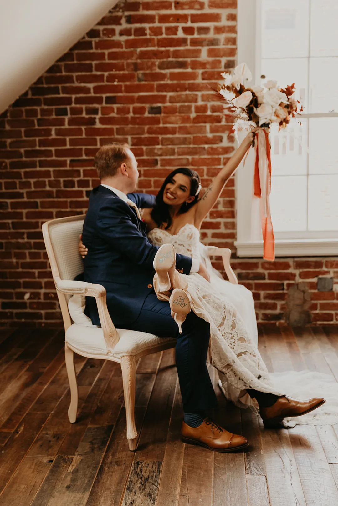 Bride and groom seated beside a decorated window