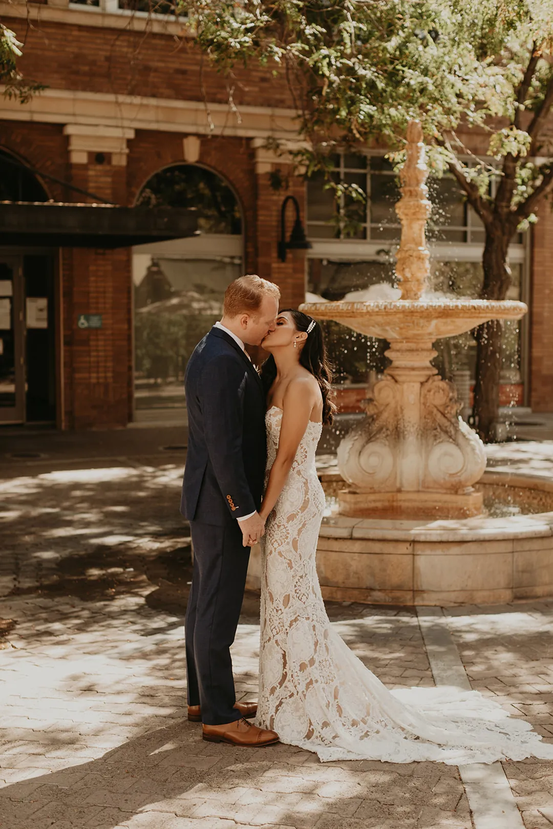 Newlyweds embracing beside an outdoor fountain