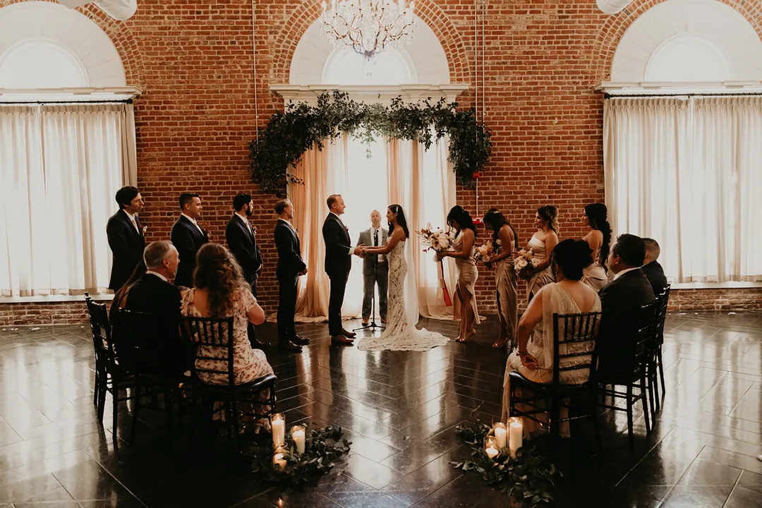 Guests watching a wedding ceremony in the brick ballroom