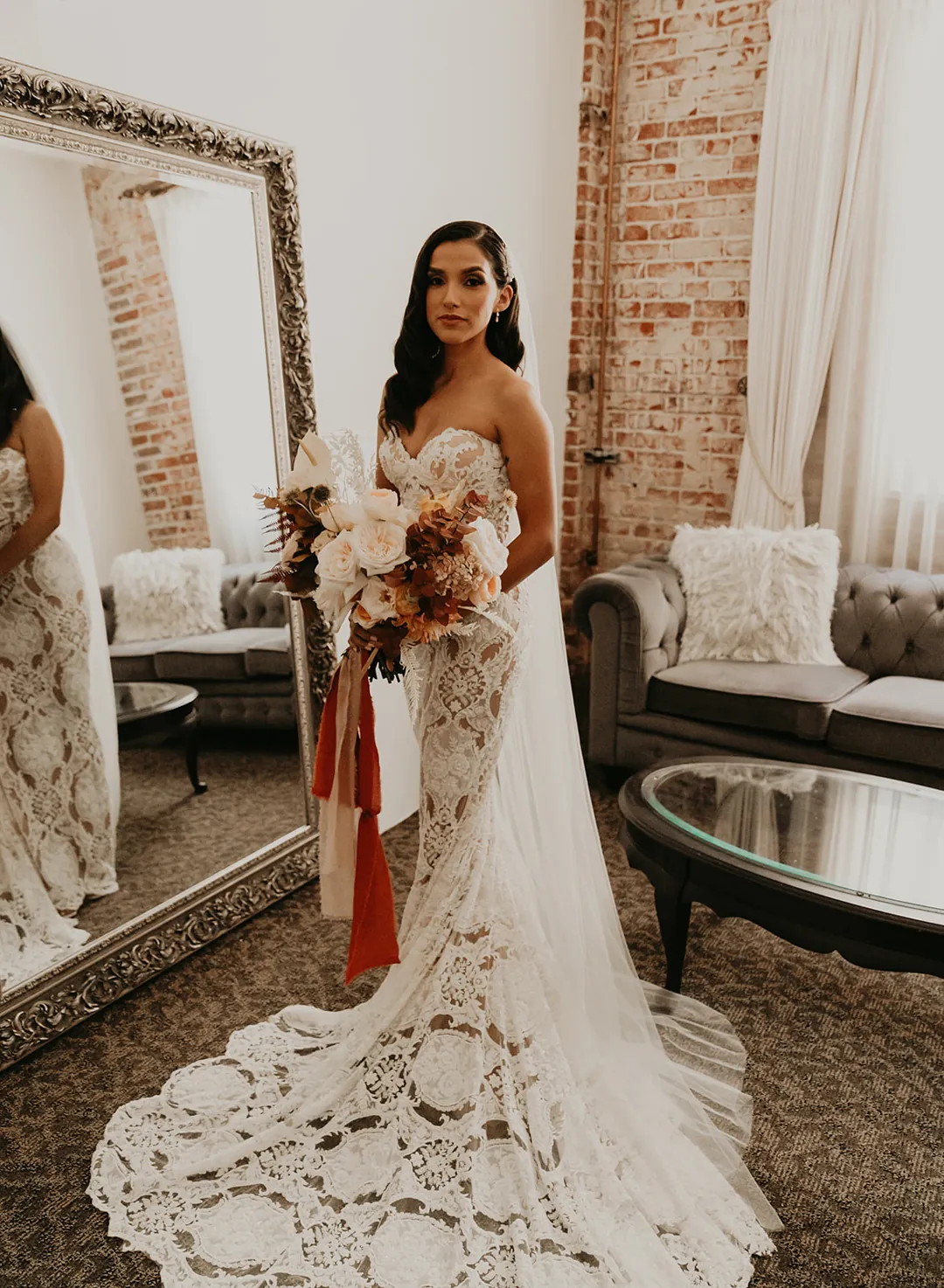 Bride standing in a lace gown with a trailing bouquet