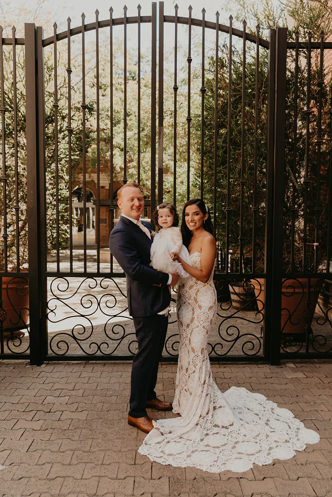 Bride and groom posing beside the venue's iron gate
