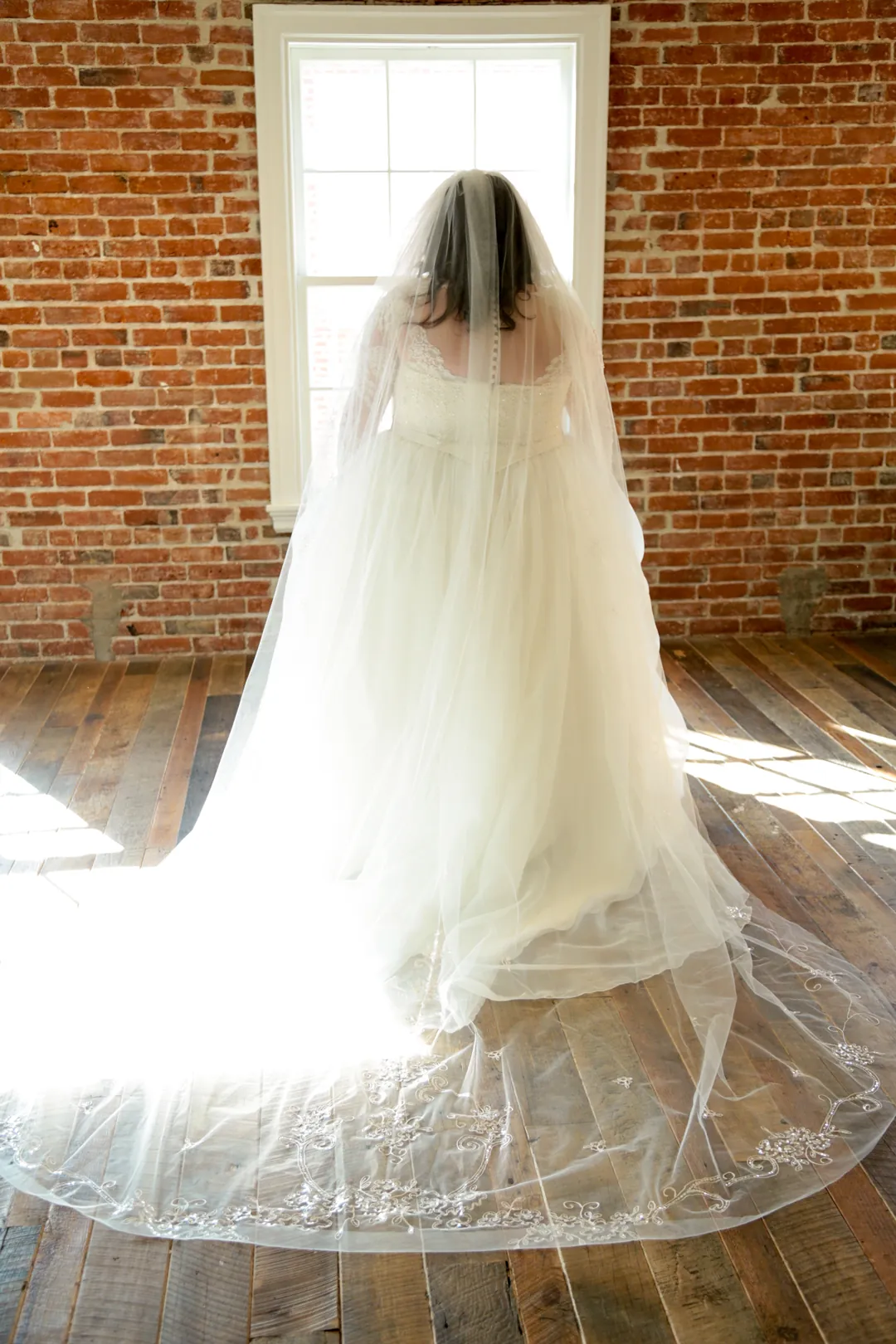 Bride's long veil and train beside a window.