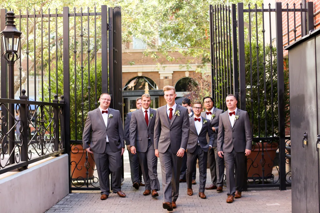 Wedding party pose at an open iron gate.