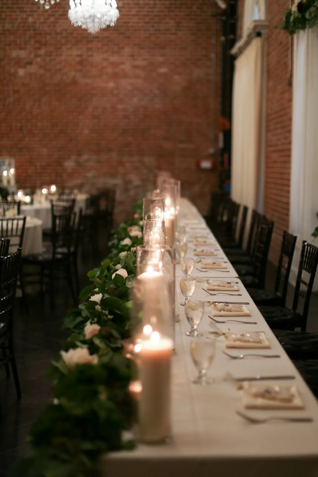 Candles and greenery decorate a long reception table.