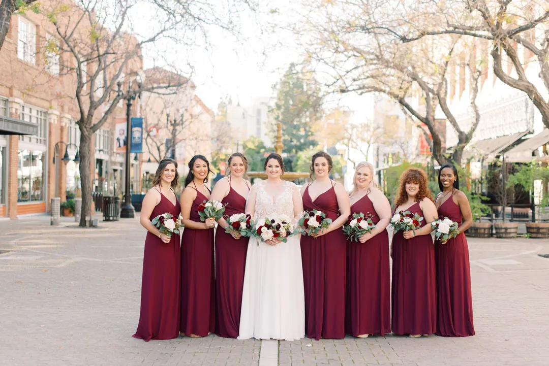 Bride and bridesmaids holding bouquets on a city sidewalk