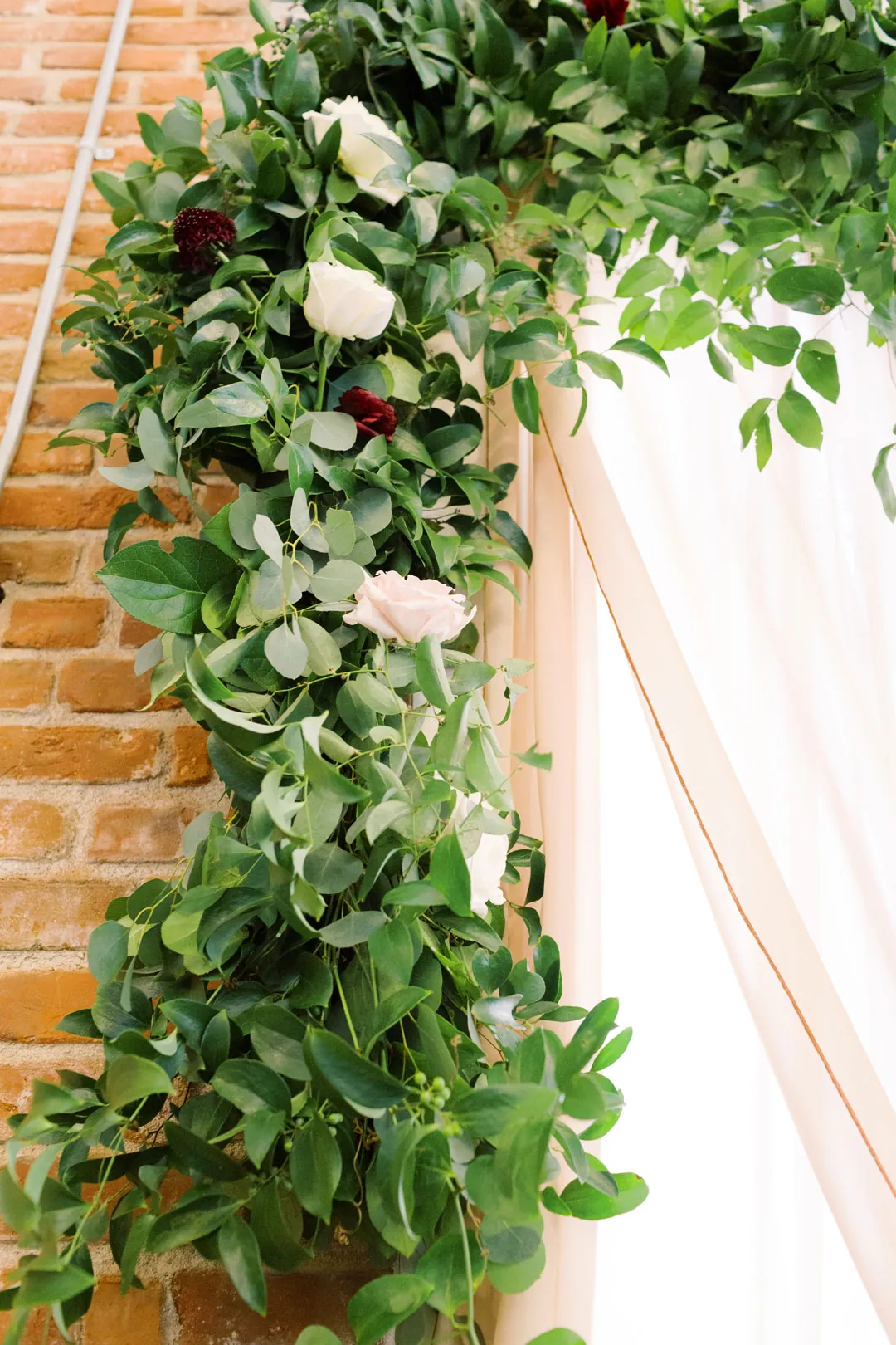 Greenery and pale flowers framing a ceremony backdrop
