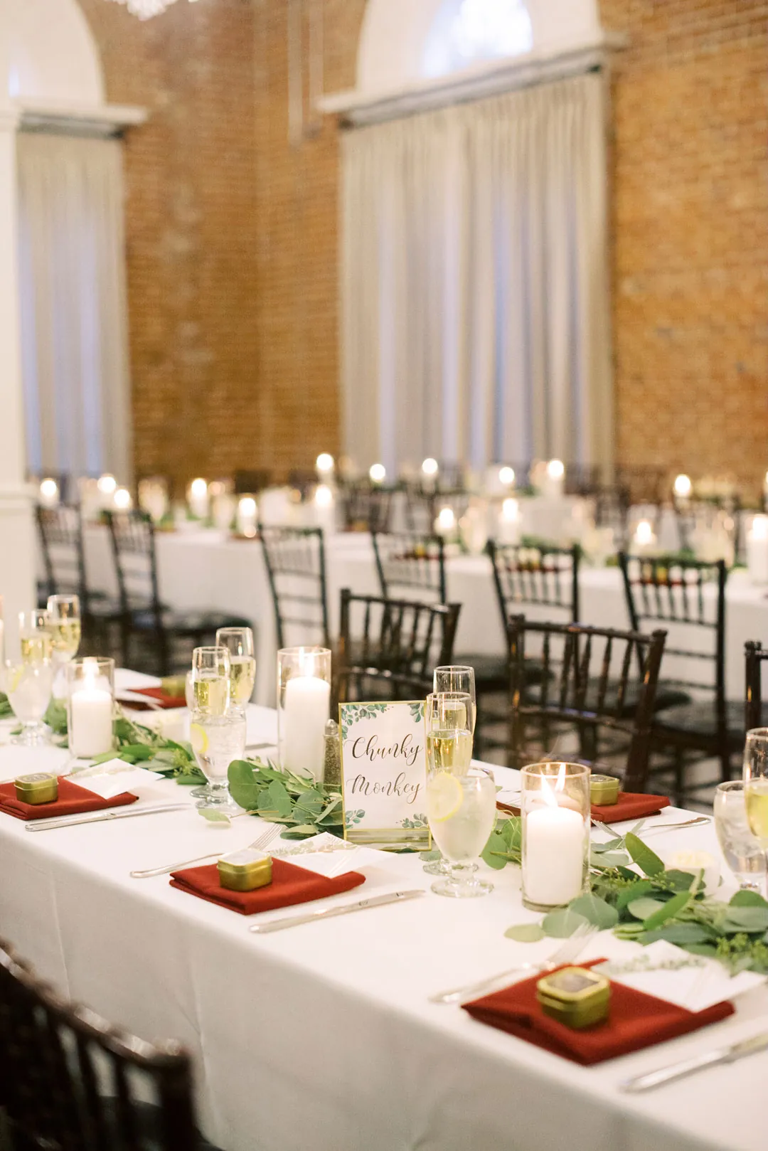 Reception table set with greenery and red napkins