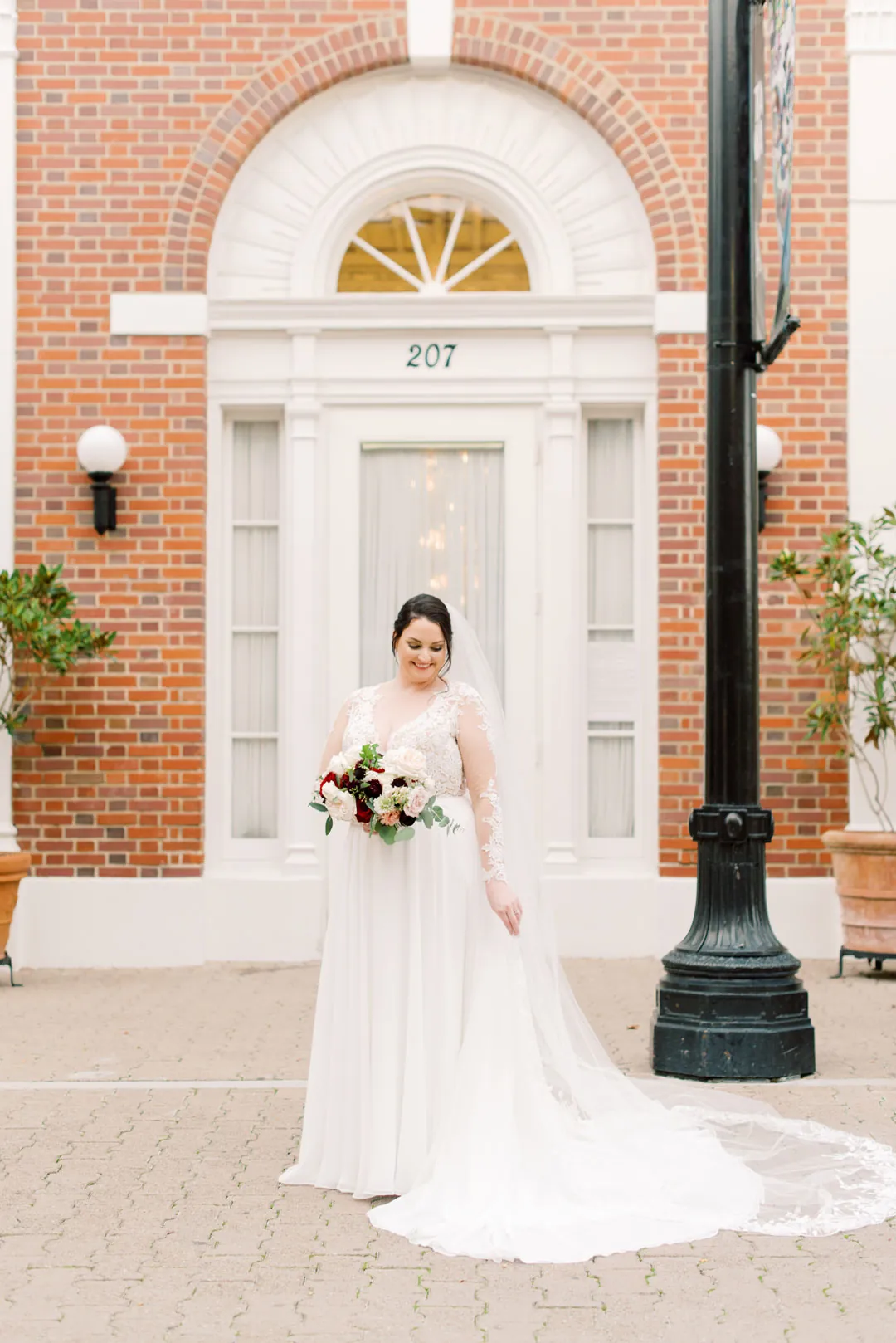 Bride holding a bouquet before a white doorway