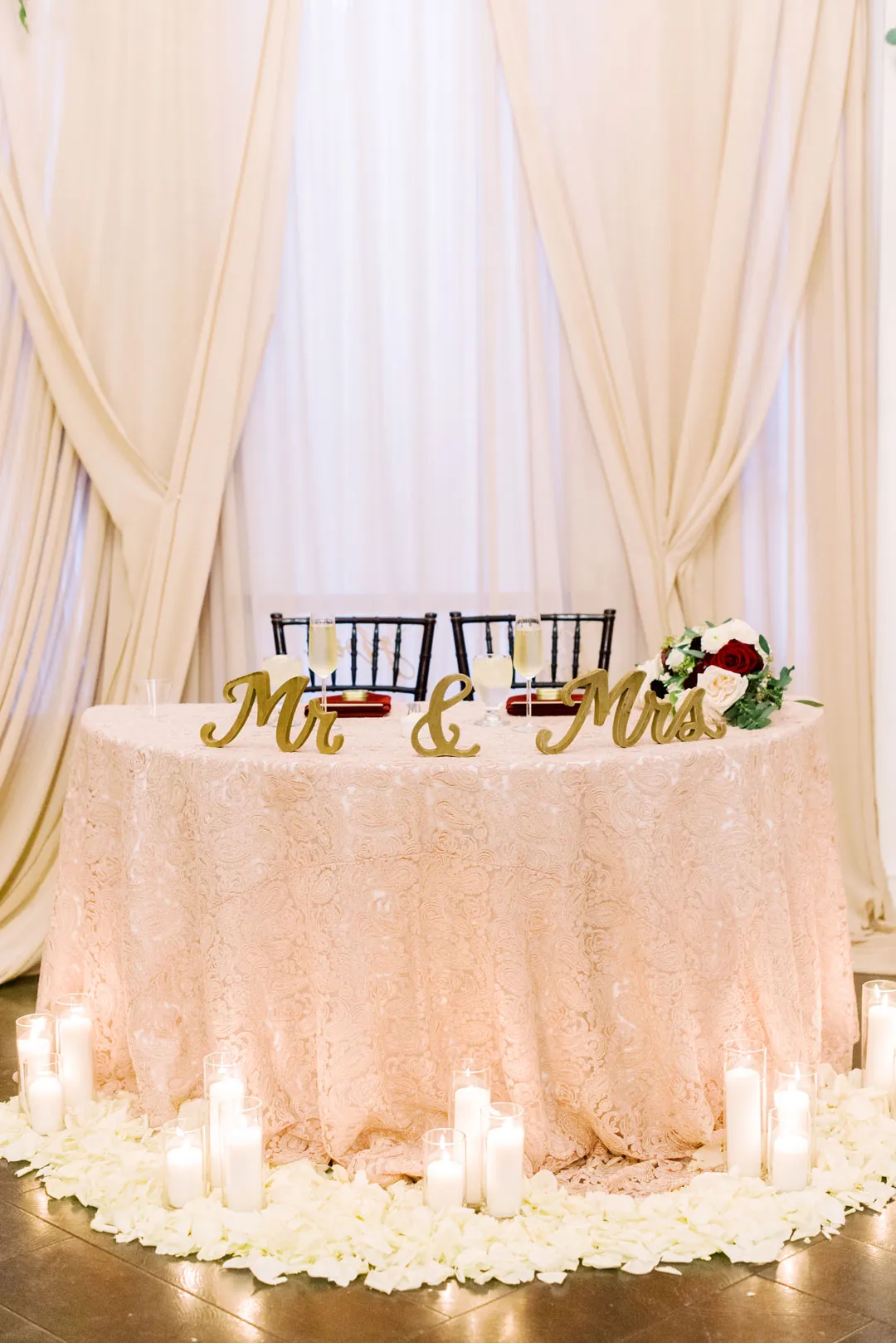 Sweetheart table with gold lettering and pale drapes