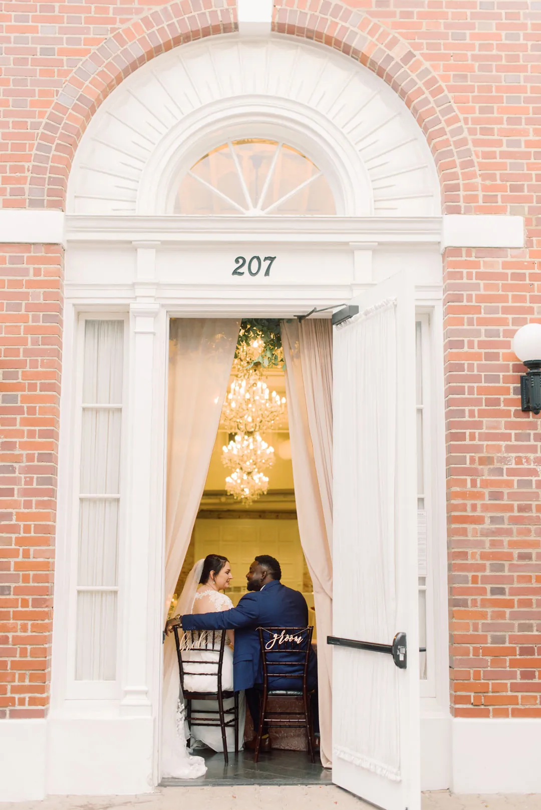 Couple seated inside an open doorway in a brick building