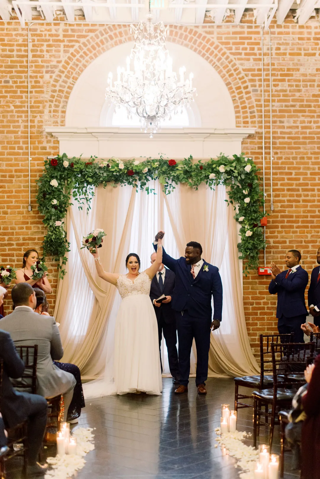 Newlyweds walking down the aisle beneath a chandelier
