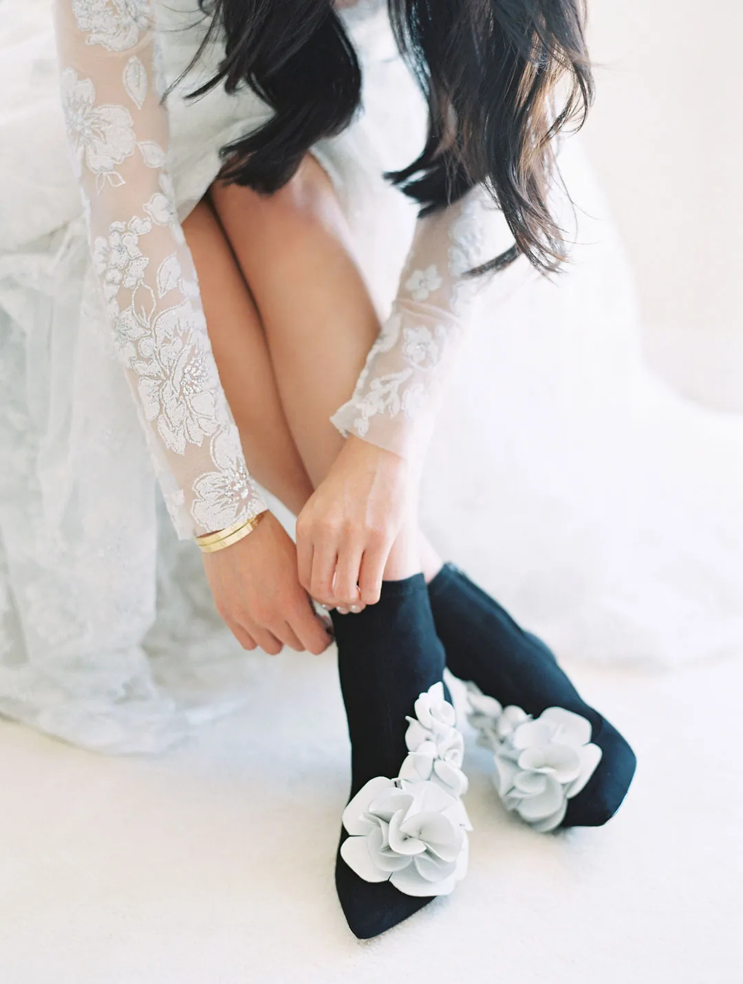 Bride fastening a black shoe decorated with flowers