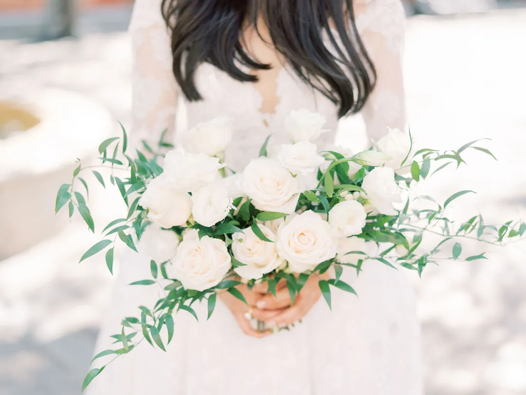 Bride holding a white rose bouquet with greenery