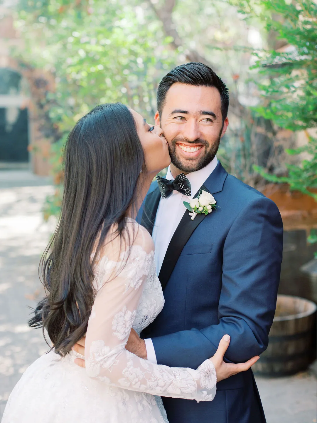 Bride kissing the groom's cheek outdoors
