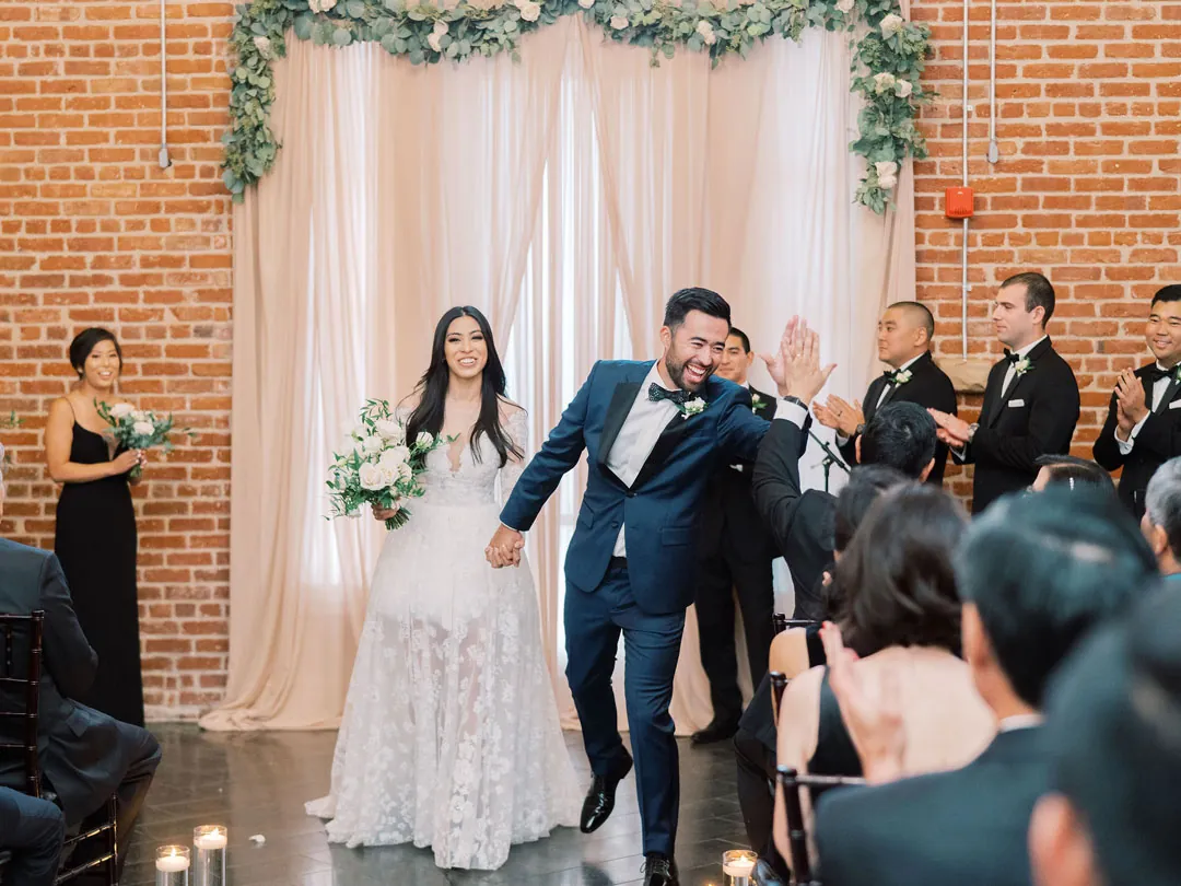 Newlyweds leaving the ceremony as guests applaud