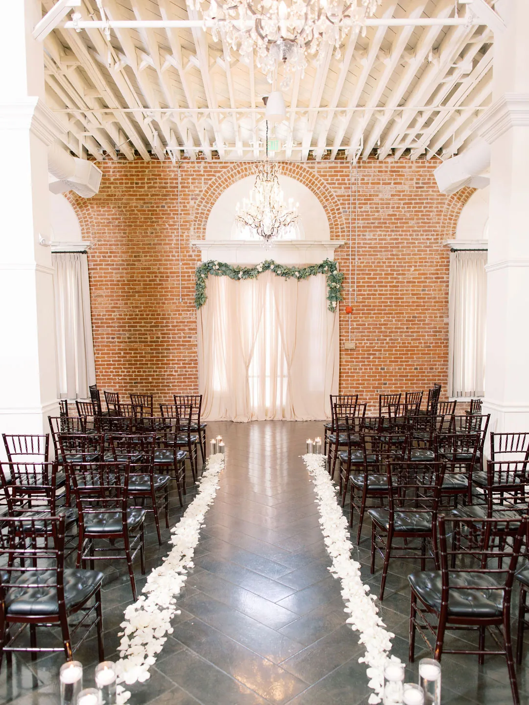 Rows of black ceremony chairs beside a flower-lined aisle