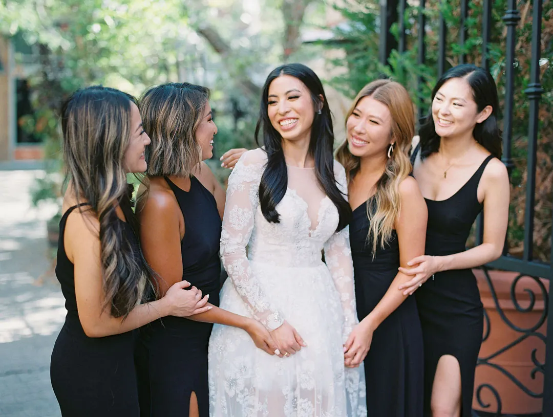 Bride and bridesmaids laughing together on an outdoor terrace