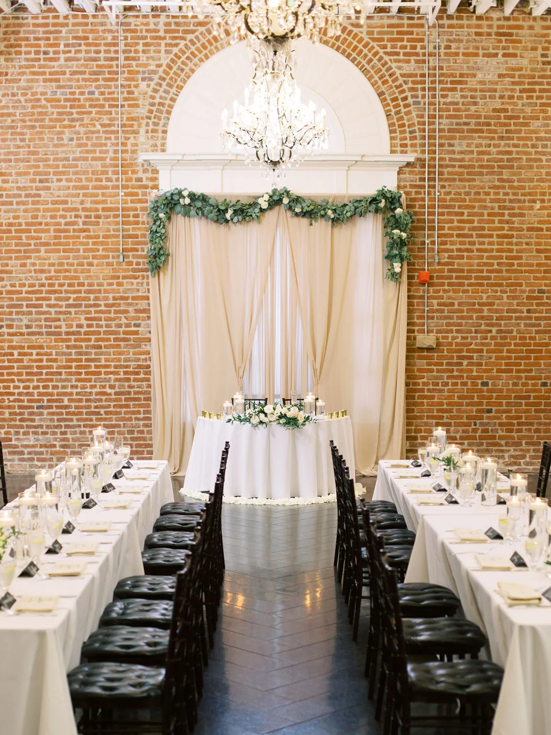 Reception tables framing a center aisle beneath a chandelier