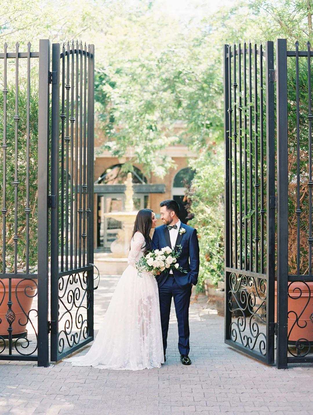 Couple standing together beneath an open iron gate