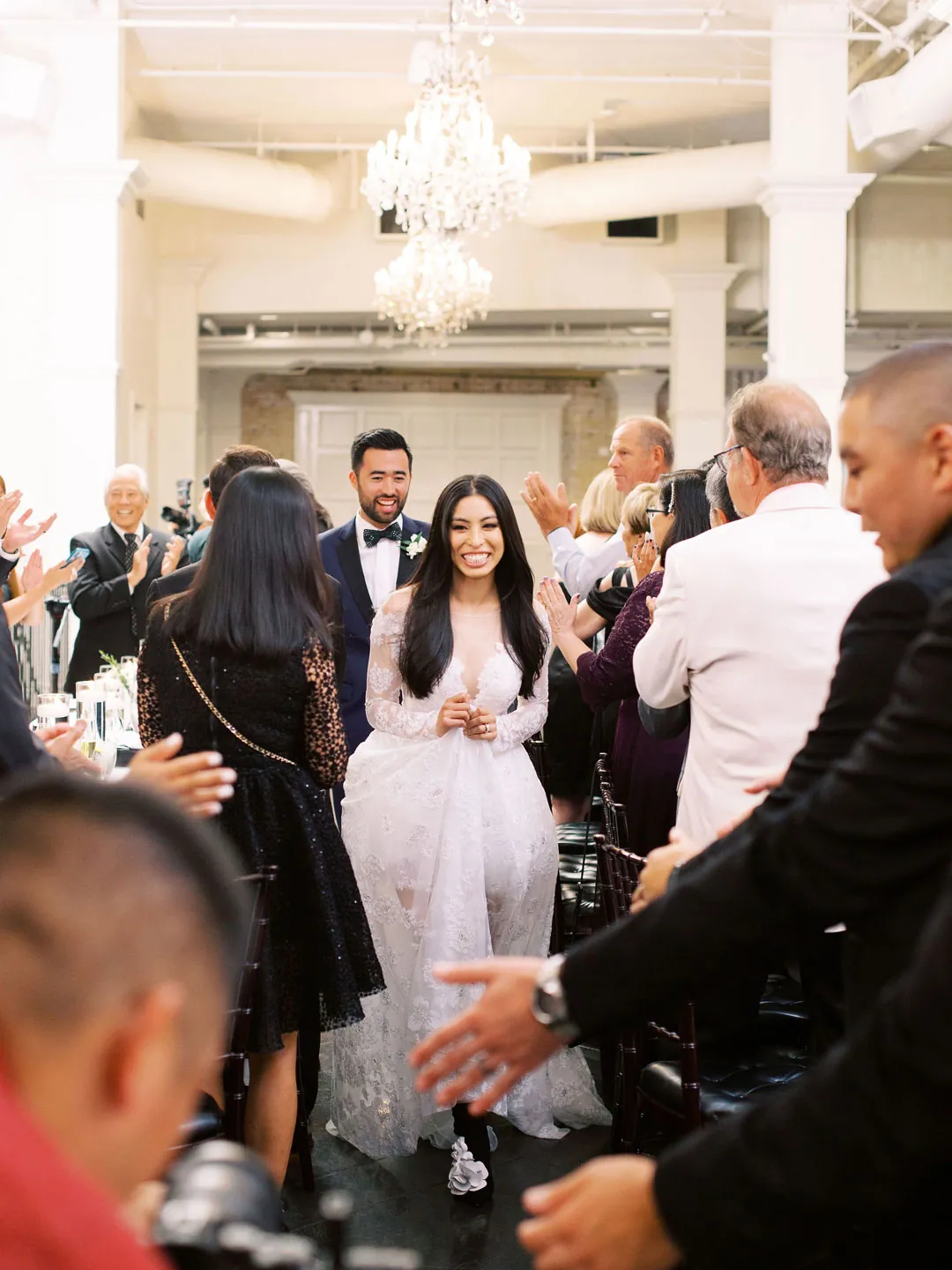 Newlyweds entering their reception as guests welcome them