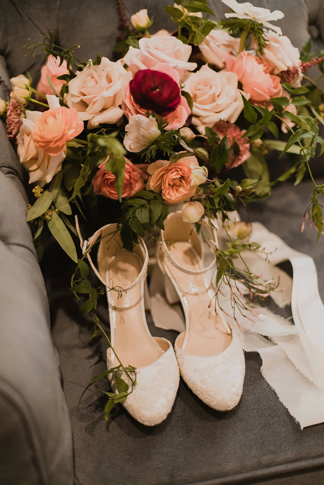 Pink and orange rose bouquet beside white heels