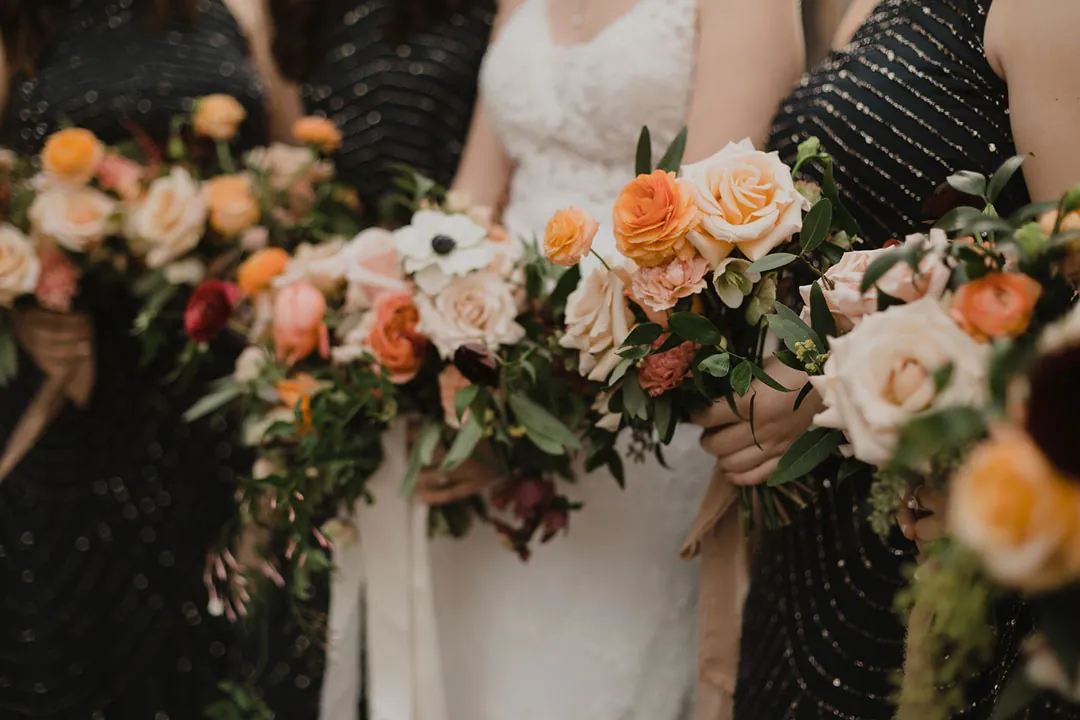 Bride and attendants holding orange and pink bouquets