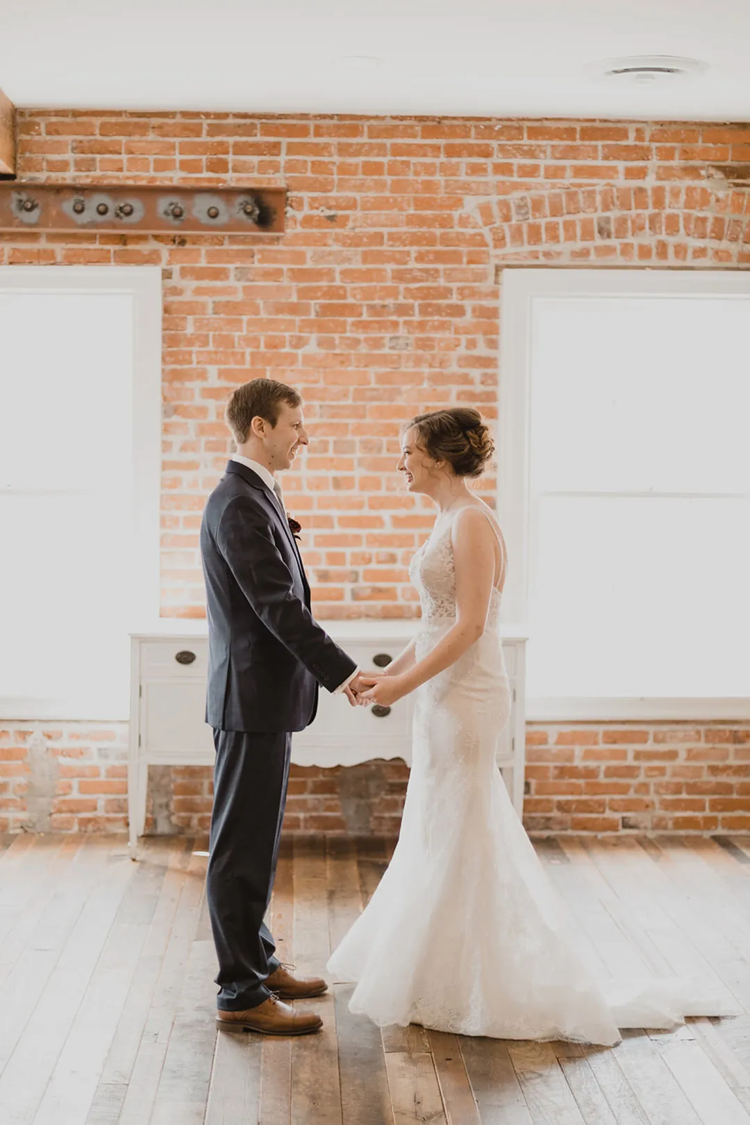 Couple holding hands in a sunlit brick loft