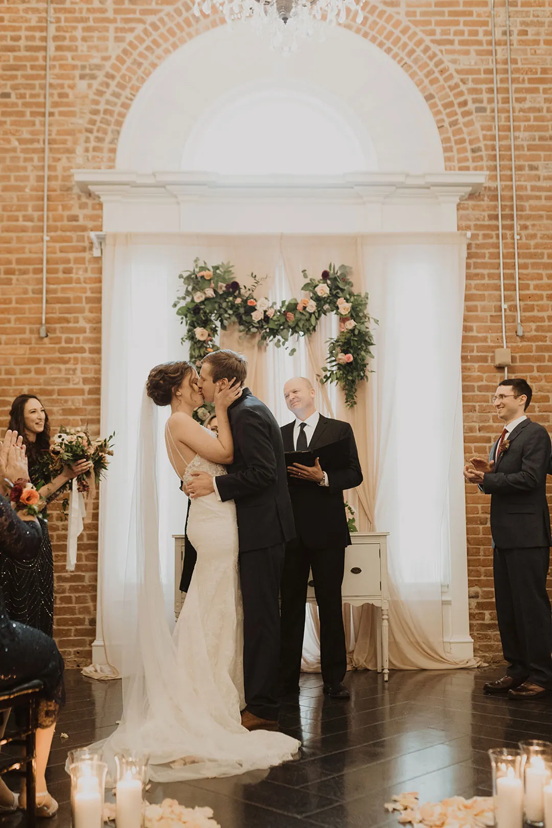 Couple exchanging vows in front of a floral backdrop