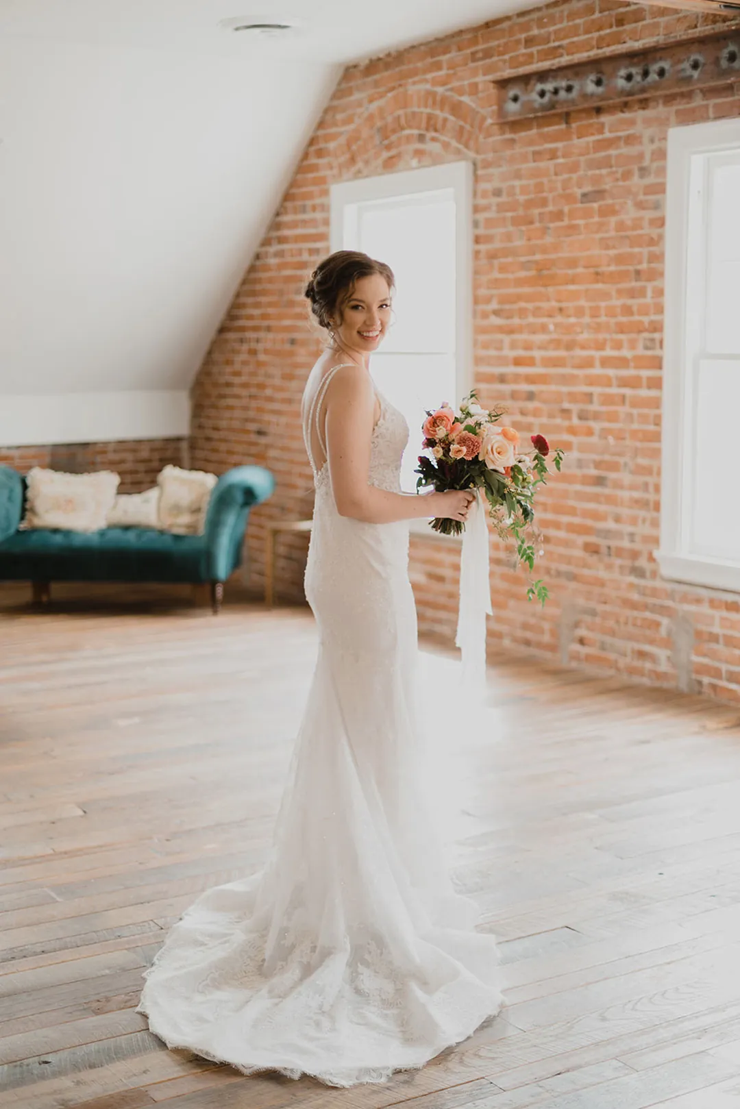 Bride holding a bouquet beside a loft window